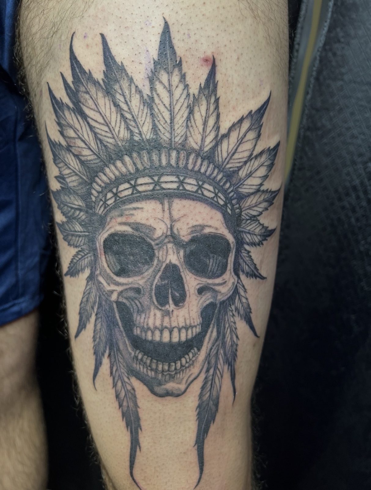 Blackwork skull wearing a leaf headdress, tattooed on the thigh